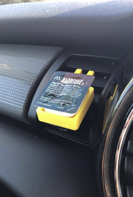 Yellow 3D printed sauce holder clipped onto car air vent holding a McDonald's BBQ sauce pot