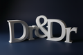 White 3D printed Dr & Dr sign on dramatic dark navy background with moody lighting