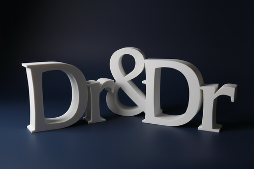 White 3D printed Dr & Dr sign on dramatic dark navy background with moody lighting